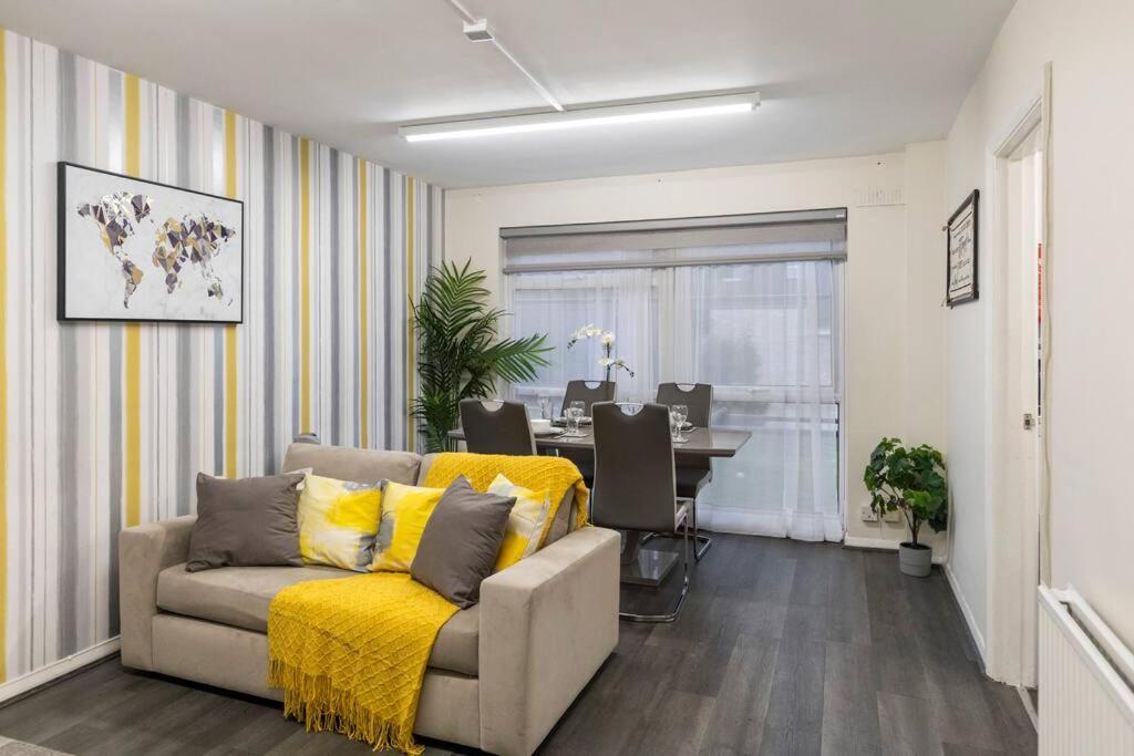 uma sala de estar com um sofá com um cobertor amarelo em Charming 1-BR Flat in Prime North London Location em Londres