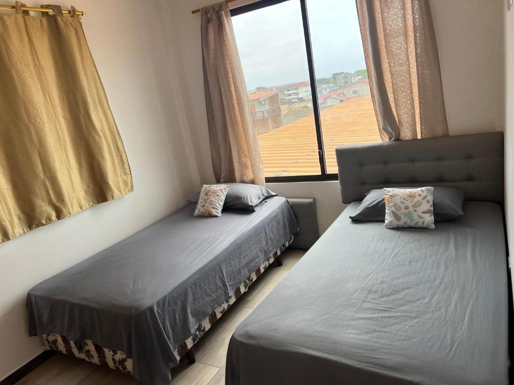 two beds in a room with a window at CONDOMINIO MIRAMAR VISTA AL MAR Playas villamil in Playas