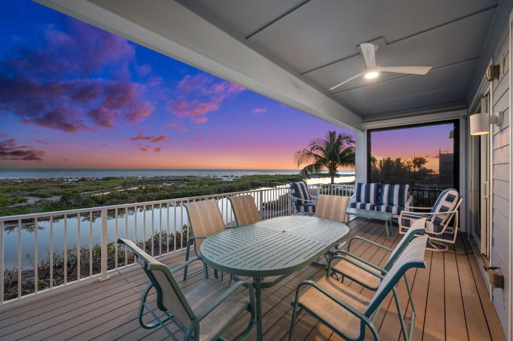 balcón con mesa, sillas y vistas al océano en Papa's Boat House - 8214 Estero Blvd home en Fort Myers Beach