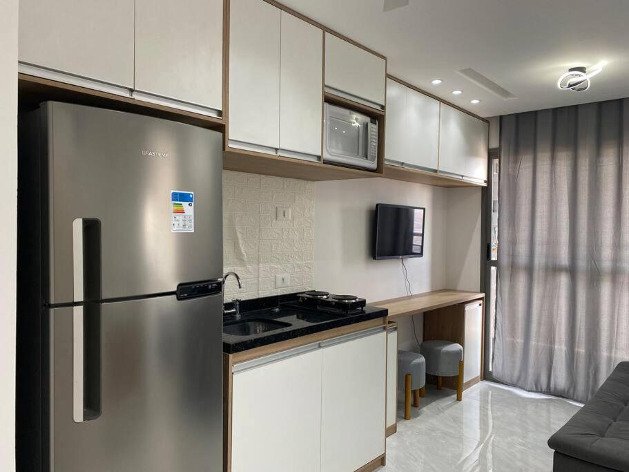 a kitchen with a stainless steel refrigerator and white cabinets at Apto ao lado do metrô de SP in Sao Paulo