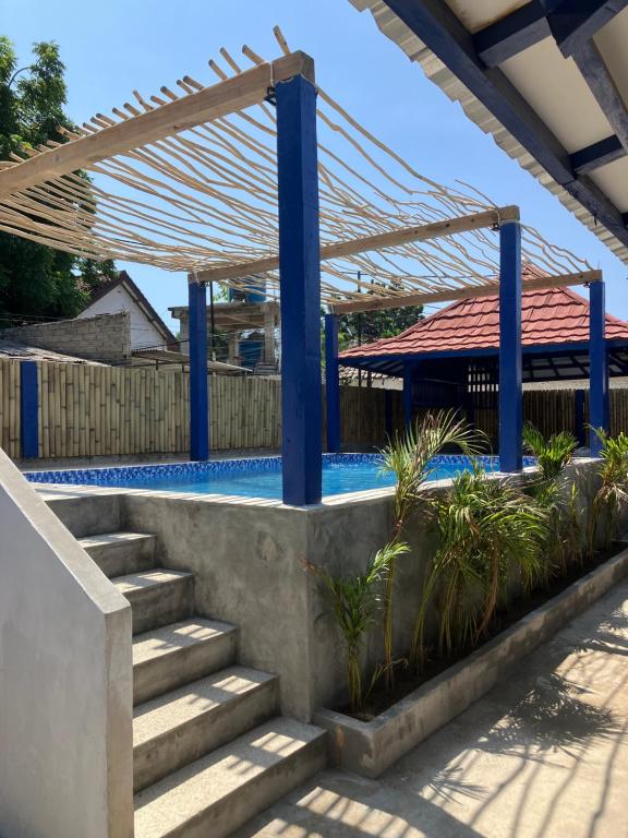 a swimming pool with stairs and a pavilion at Hostel Gili Trawangan in Gili Trawangan