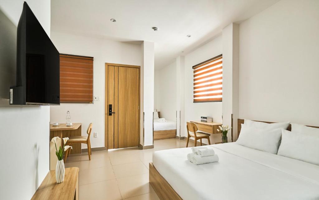a bedroom with a bed and a desk and a television at MIHN SUITES BEN THANH in Ho Chi Minh City