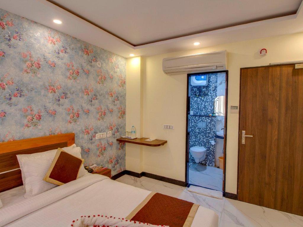 a bedroom with a bed and a door to a bathroom at Jasoda Heritage By Keshav Global Hotels in Jaipur