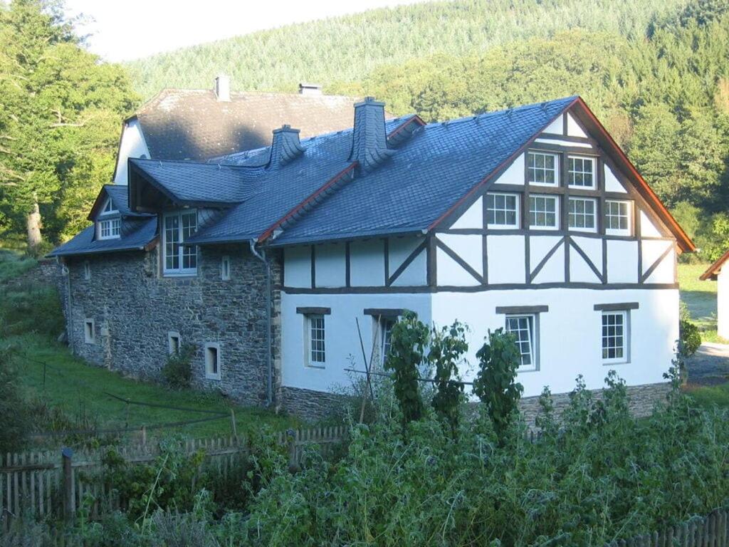 una casa bianca con un tetto nero su una collina di Romantische molen schuur huisdieren welkom a Beuren