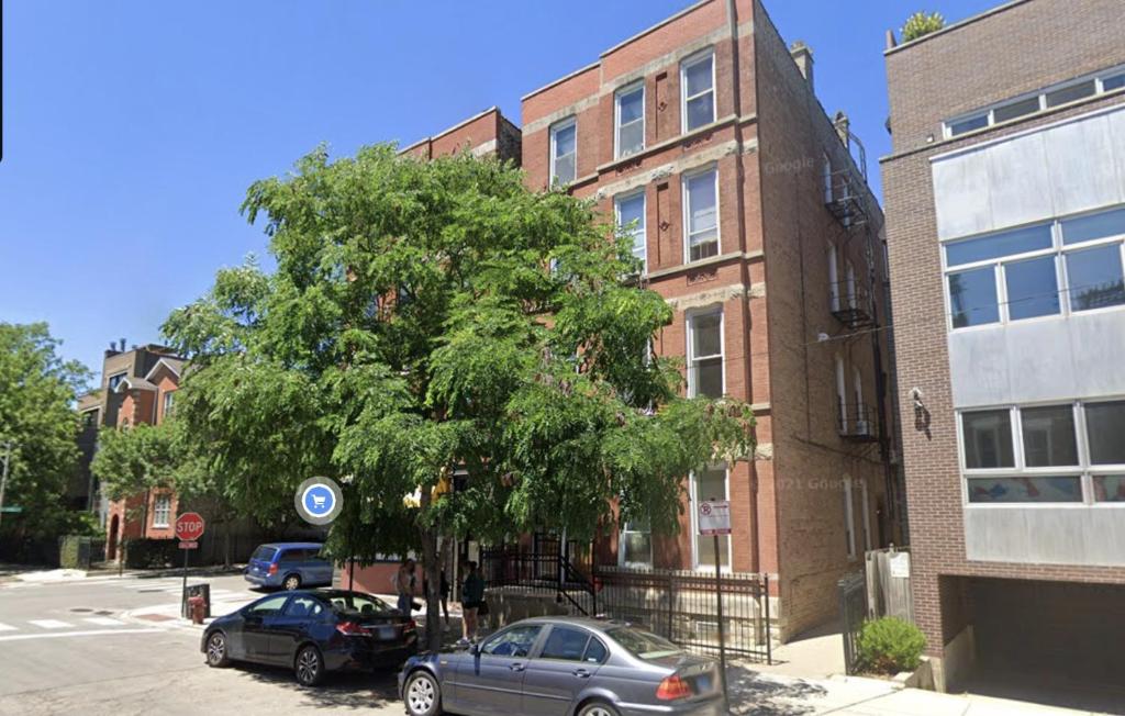 a tree in front of a building with cars parked next to it at The Secret West Loop Oasis in Chicago