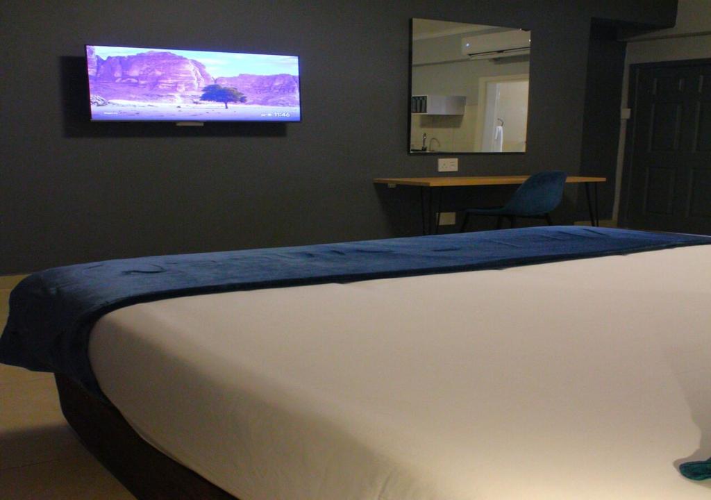 um quarto com uma cama e uma televisão na parede em Bayside Self Catering and Hotel 14 Monty Naicker Pinestreet Durban em Durban