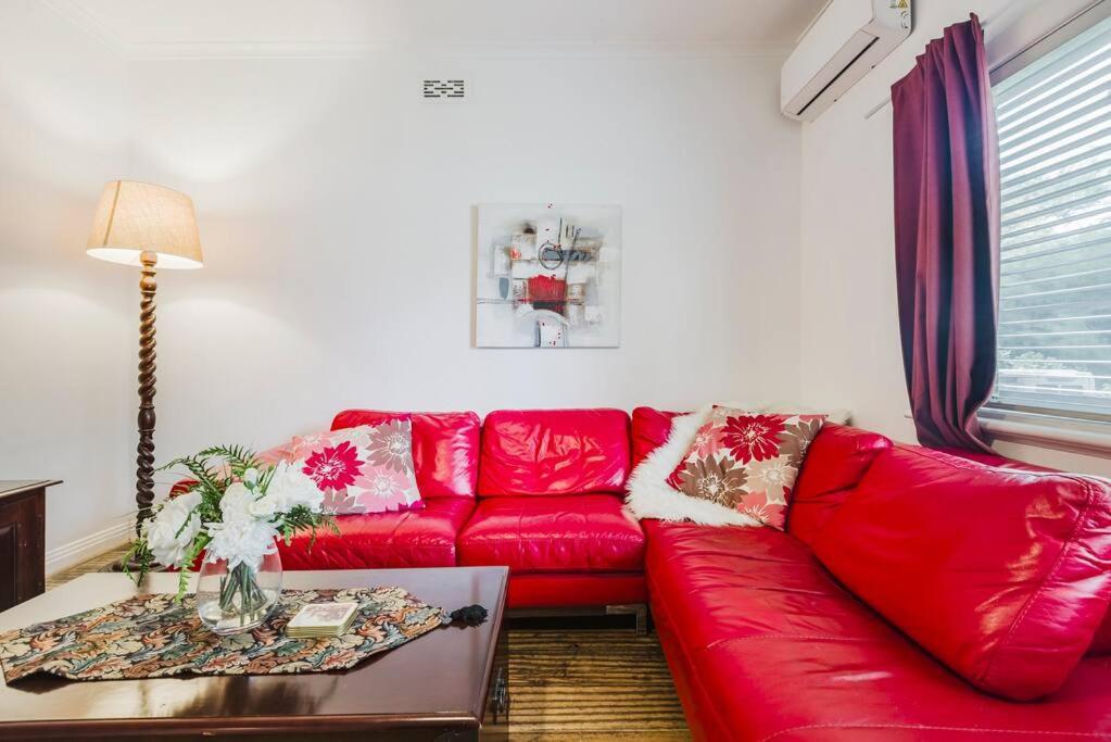 un canapé rouge dans un salon avec une table dans l'établissement Yarraville Garden Large home with yard and parking, à Yarraville