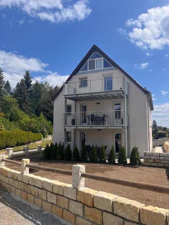 a large white house with a stone wall at Ferienwohnung Papststeinblick in Kurort Gohrisch