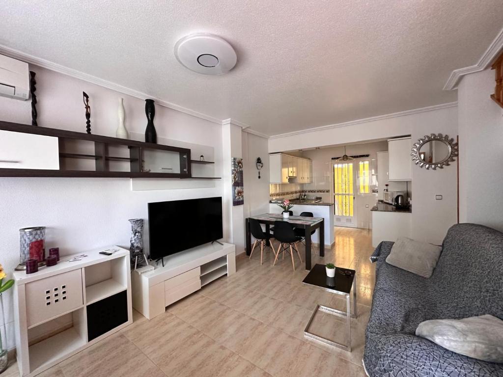 a living room with a couch and a tv and a table at Nice 3 bedroom Duplex Cabo Roig in Orihuela Costa