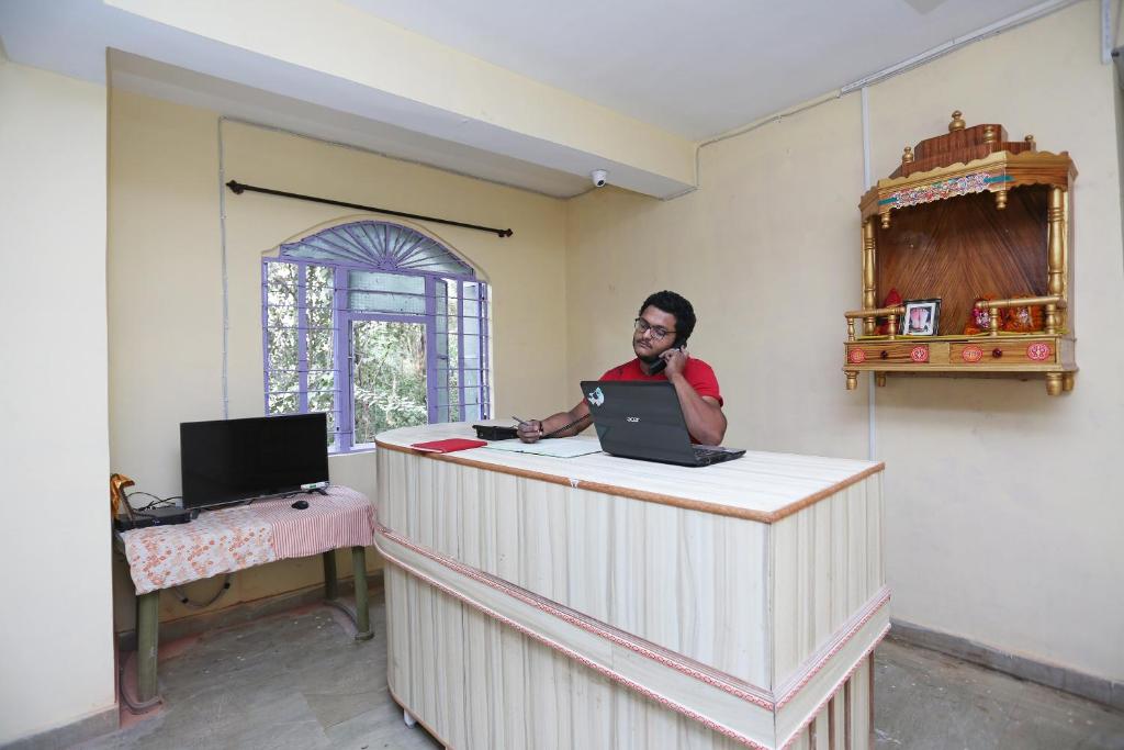 a man sitting at a counter with a laptop at OYO Flagship Hotel New Urvashi in Hājīpur