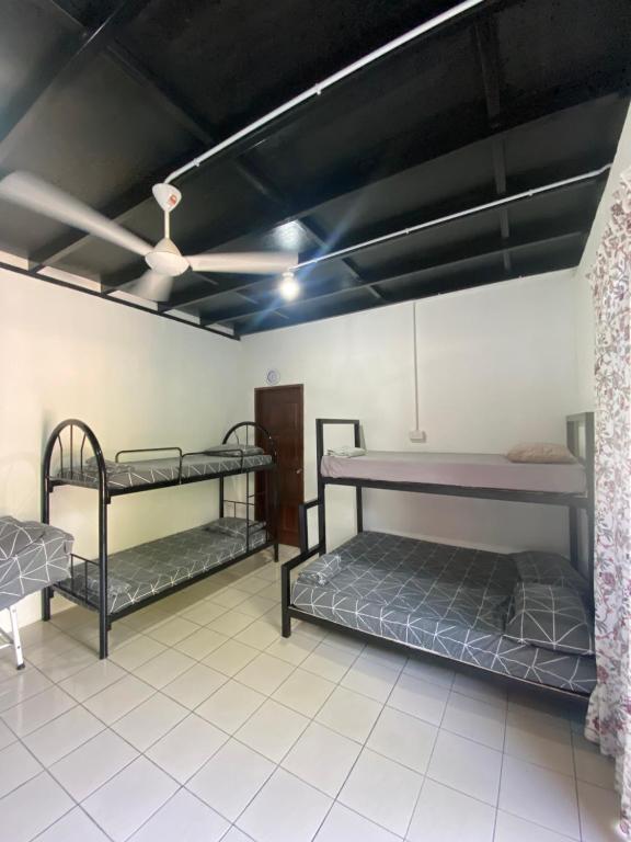 Cette chambre comprend 3 lits superposés et un ventilateur de plafond. dans l'établissement Julian Homestay, à Tuaran