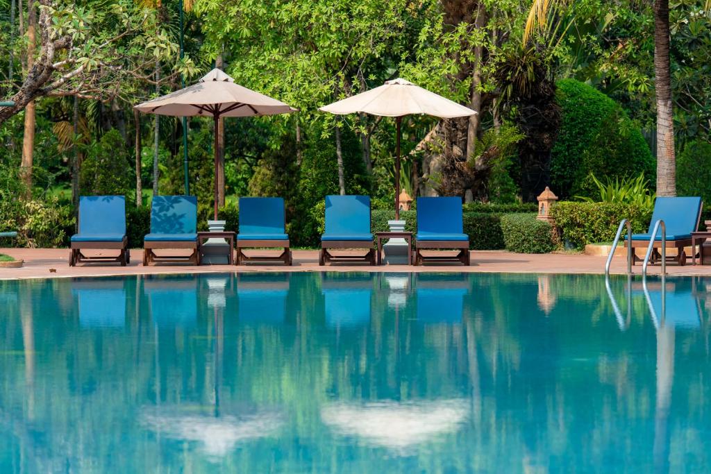 um grupo de cadeiras e guarda-sóis ao lado de uma piscina em Angkor Palace Resort & Spa em Siem Reap