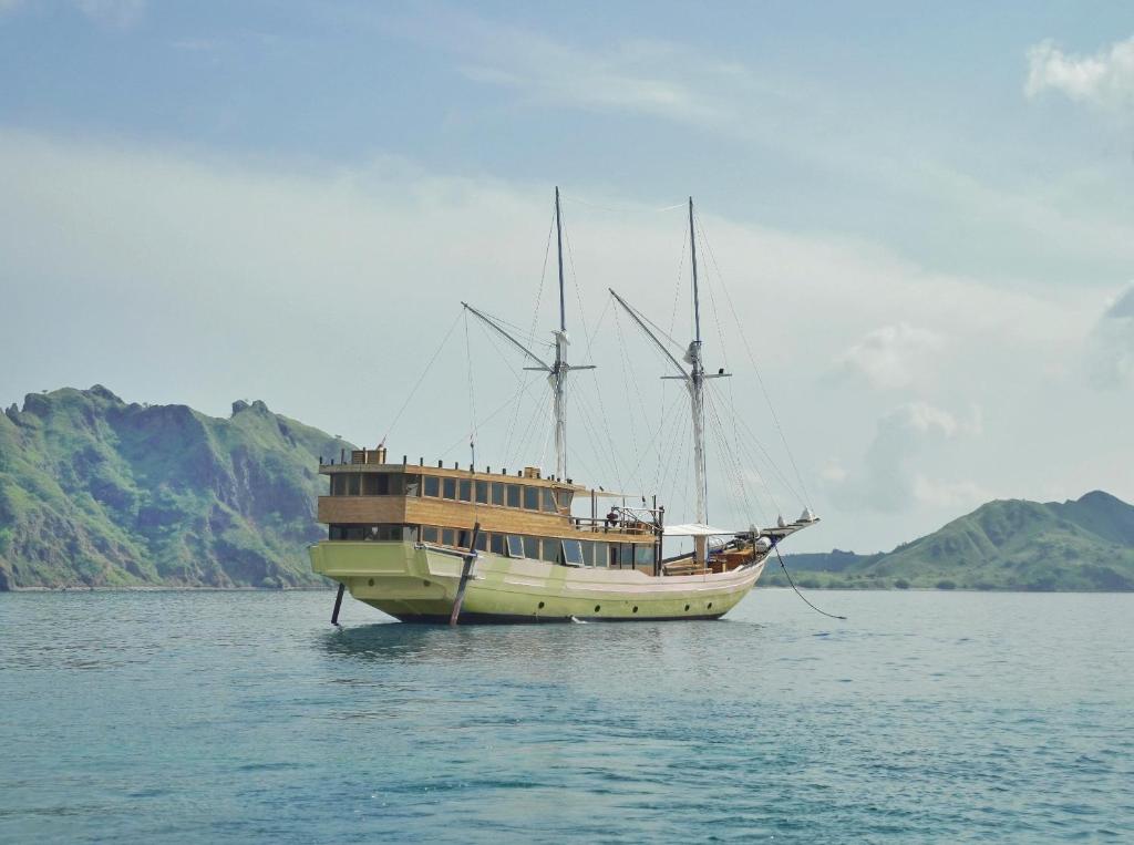 a boat in the water with mountains in the background at Leticia Liveaboard in Labuan Bajo