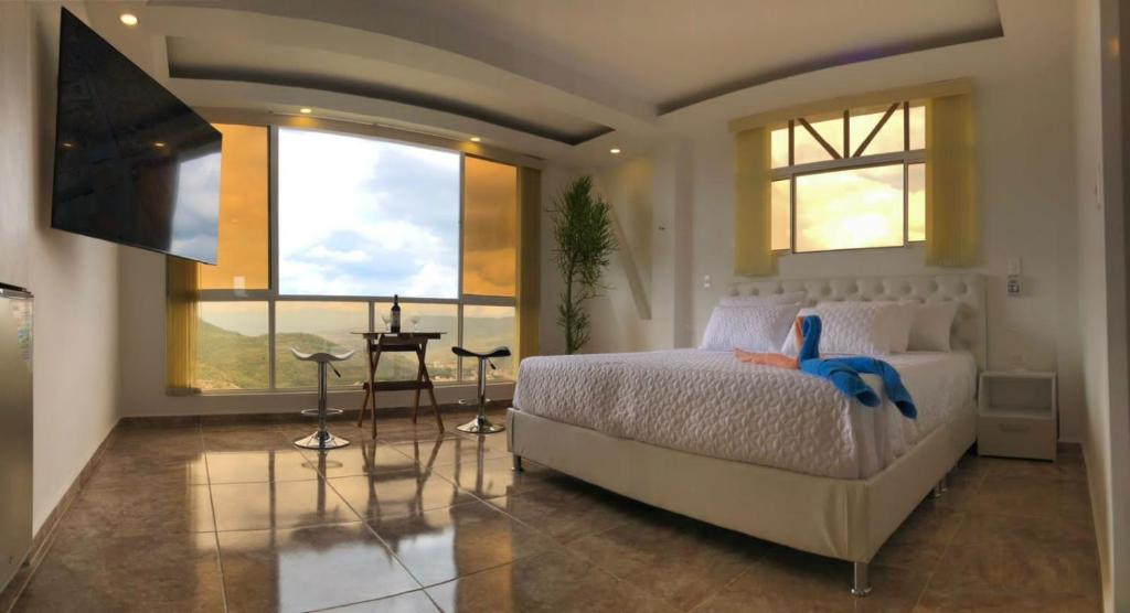 a bedroom with a bed and a large window at Apart Hotel El Gran Mirador de Palmaire San Gil in San Gil