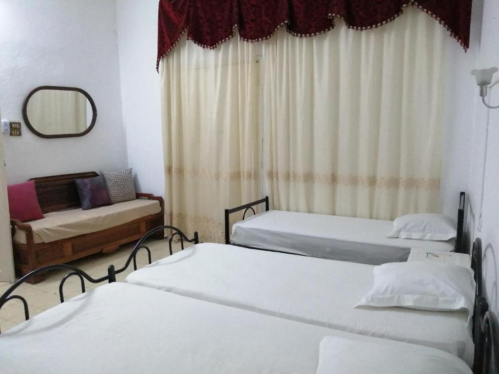 Pokój z 3 łóżkami i lustrem w obiekcie Dar manena w mieście Kairuan