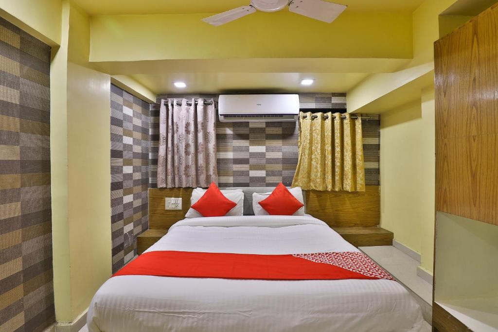 a bedroom with a large bed with red pillows at SPOT ON Hotel Shreeji Palace in Ahmedabad