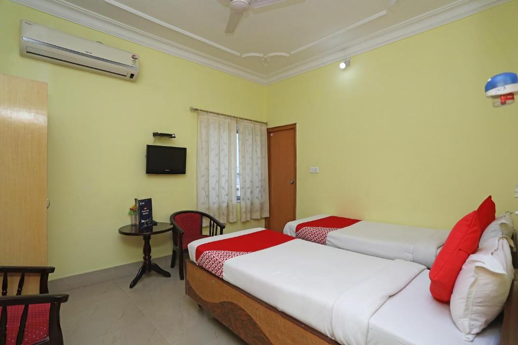 a bedroom with two beds and a table and a tv at OYO Hotel Kanako International in Bodh Gaya
