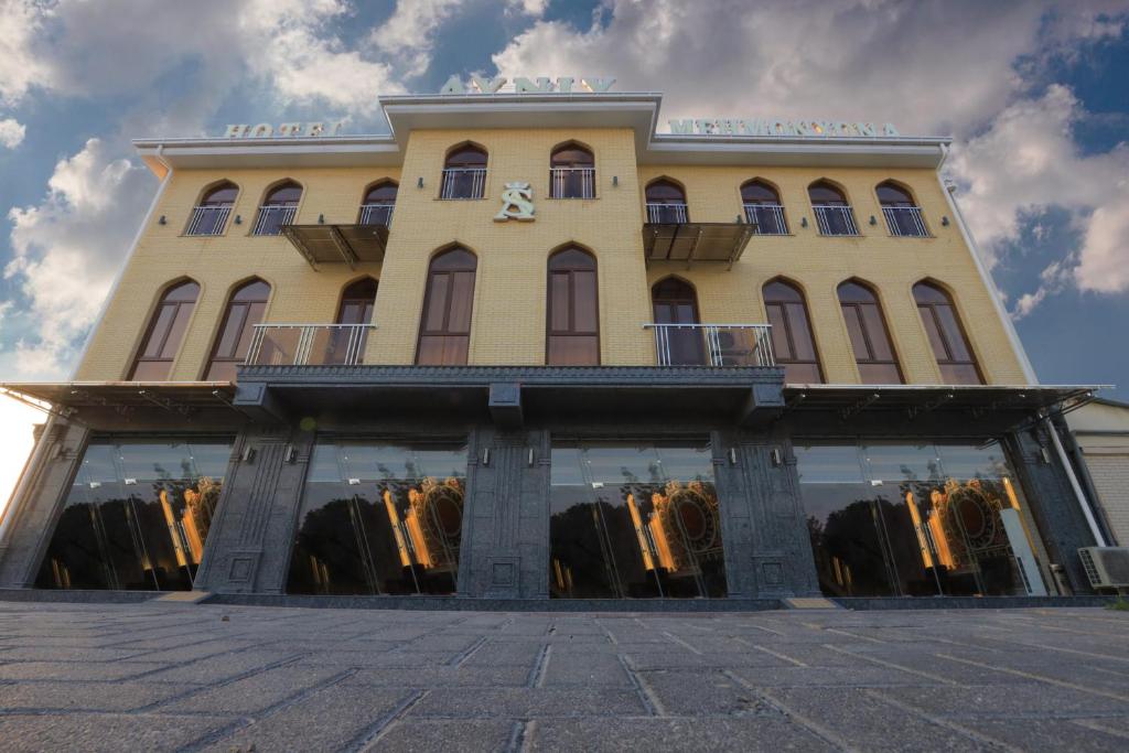 ein großes gelbes Gebäude mit vielen Fenstern in der Unterkunft AYNIY Hotel in Samarkand