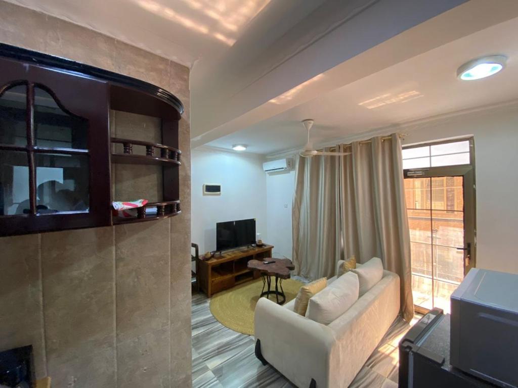 a living room with a couch and a tv at maasaifari cozy homes in Dar es Salaam