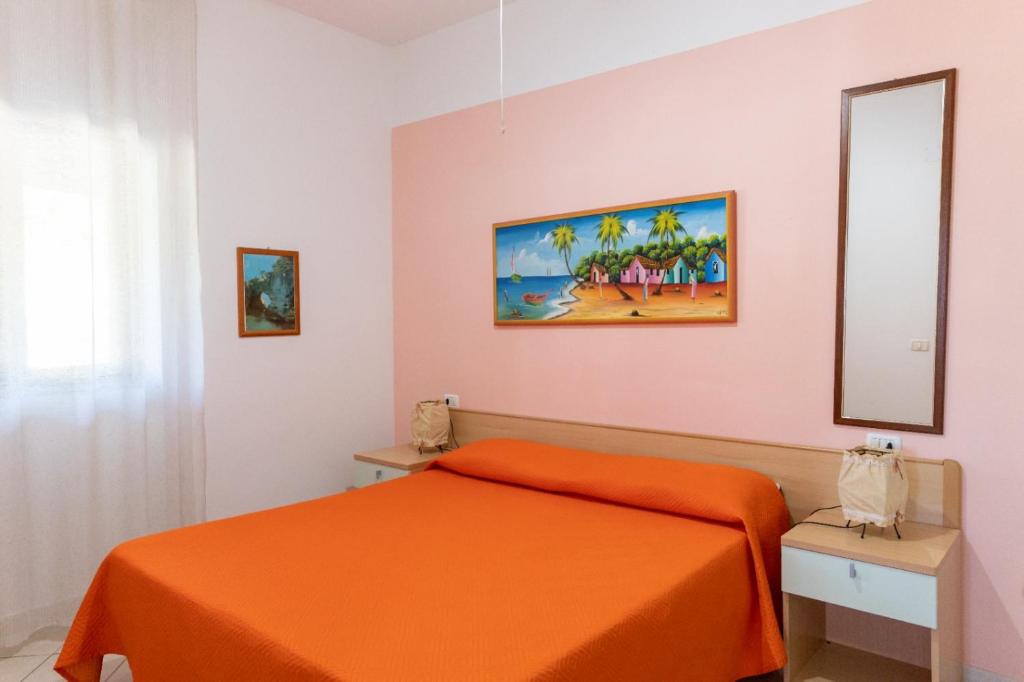 sypialnia z pomarańczowym łóżkiem i lustrem w obiekcie Villa Marilena w mieście Peschici
