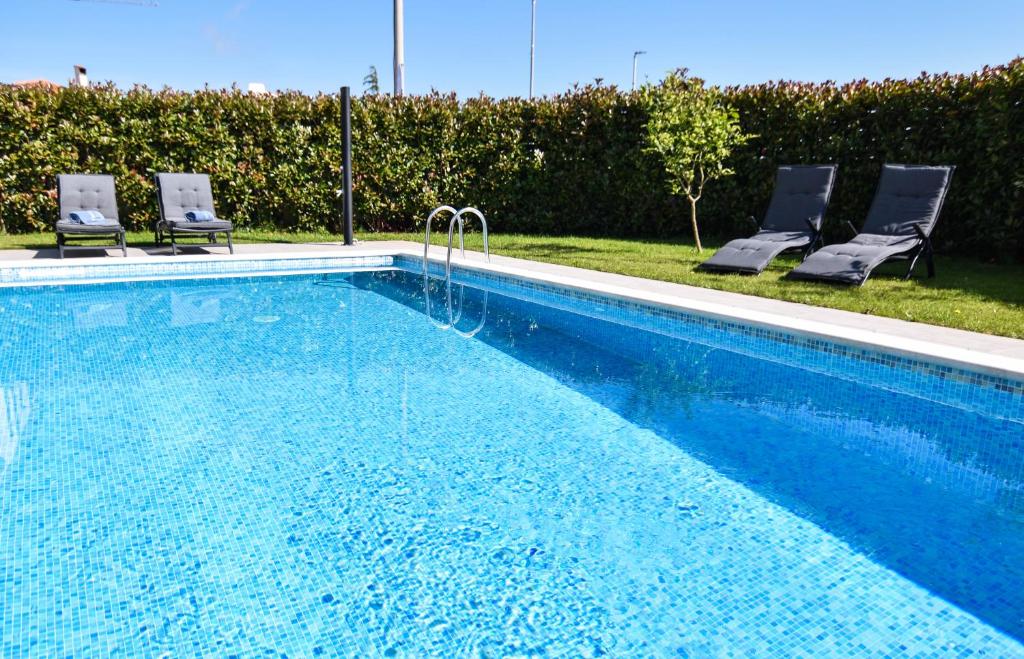 a swimming pool with two chairs at Luxury apartment Vela with swimming pool in Premantura