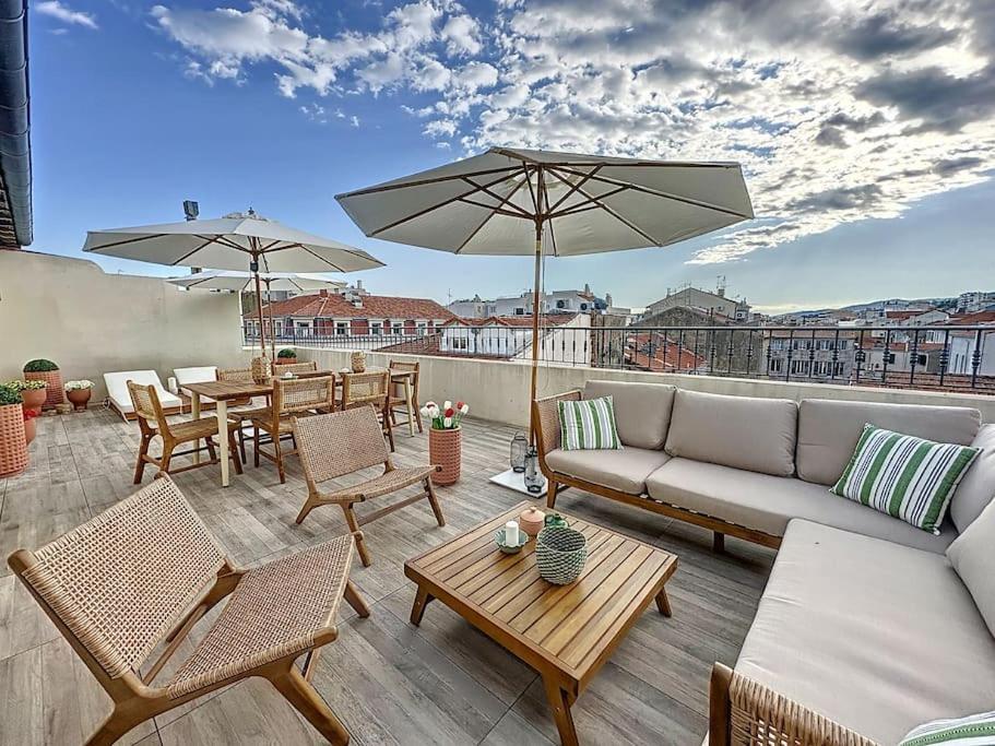une terrasse avec un canapé, des tables et des parasols dans l'établissement 79m2 Penthouse, Palais et plages à 400m rooftop, à Cannes