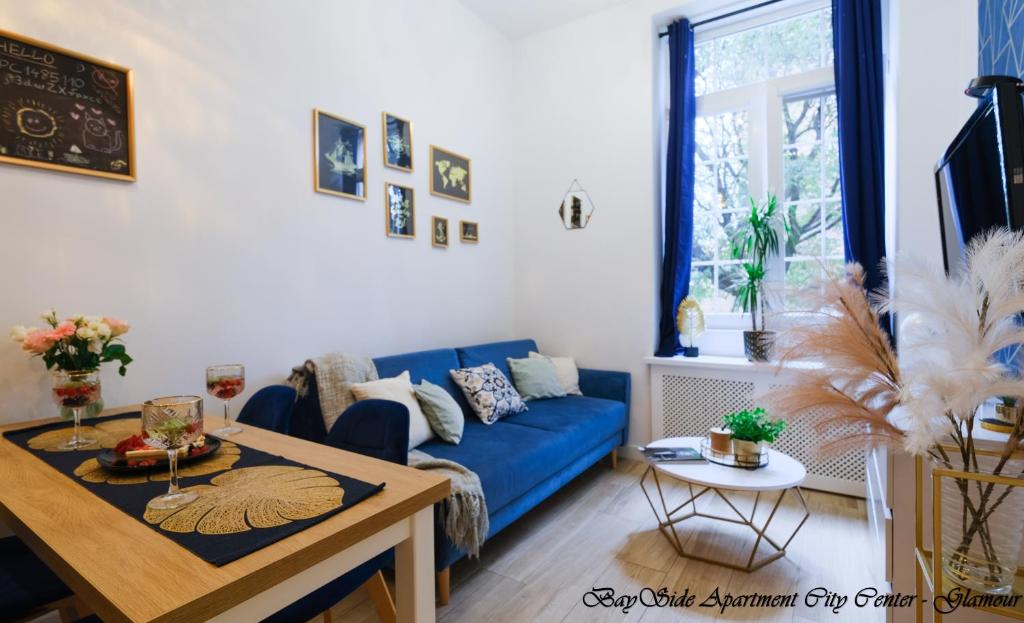 uma sala de estar com um sofá azul e uma mesa em BaySide Apartments City Center em Gdańsk