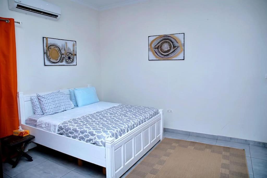 a bed in a room with two pictures on the wall at Homely stay in the heart of Osu - Studio 2 in Accra