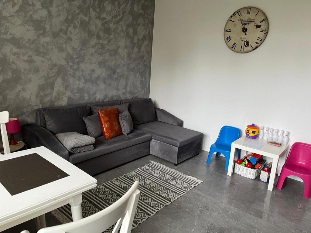uma sala de estar com um sofá e um relógio na parede em Apartament Szpitalna em Suwałki
