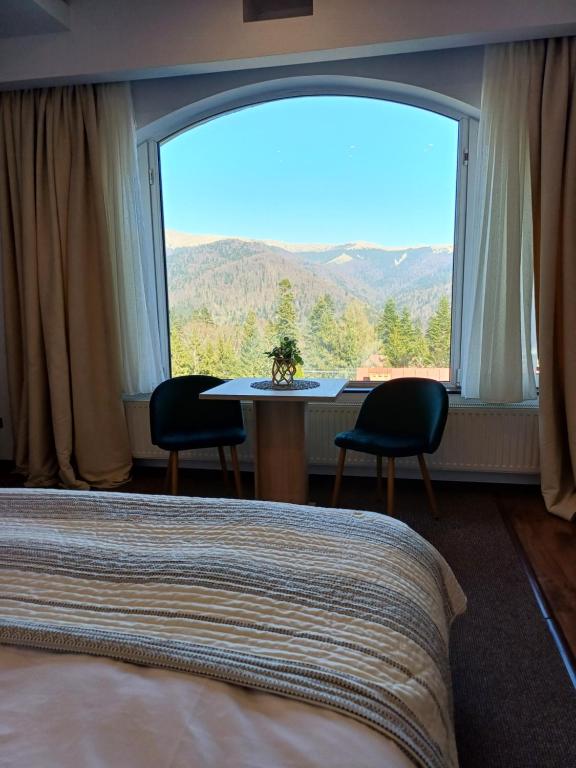 a bedroom with a large window with a table and chairs at Apartamente Private A&L View in Sinaia