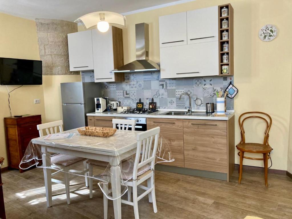 una cocina con mesa y sillas y una cocina con armarios blancos. en Casa Vacanze Il Borgo, en Gubbio