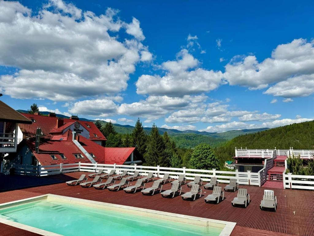 eine Terrasse mit Liegestühlen und einem Pool in der Unterkunft Wellland Hotel in Jaremtsche