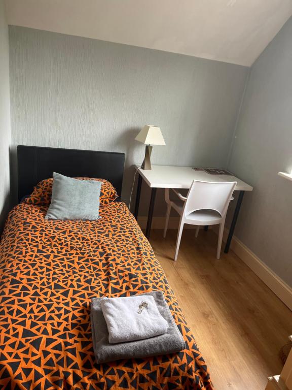 Schlafzimmer mit einem Bett, einem Schreibtisch und einem Tisch in der Unterkunft Cozy single room in private home in Dagenham