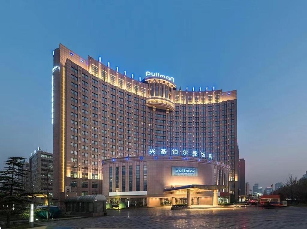 un grand bâtiment d'hôtel avec ses lumières allumées dans l'établissement Pullman Beijing South, à Daxing