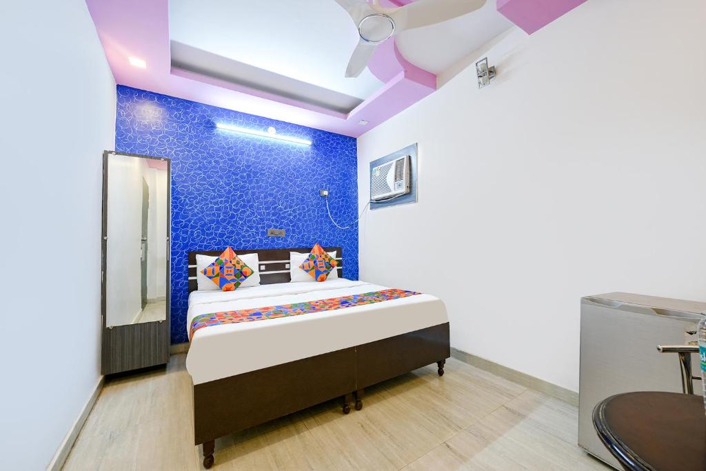 um quarto com uma cama com uma parede azul em FabHotel Capital Inn em Ghaziabad