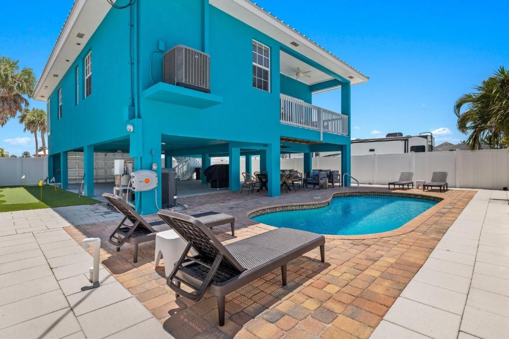 a blue building with chairs and a swimming pool at Inn-2-Blue - 155 Jefferson St home in Fort Myers Beach