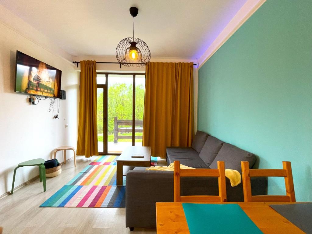 a living room with a couch and a table at Cozy Riverfront Apartments with garden and mountain view in Buşteni