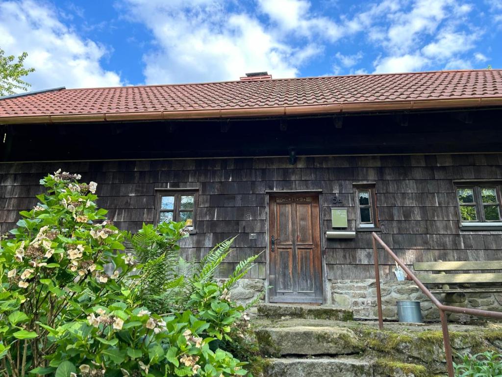 een klein houten huis met een deur en bloemen bij Ferienhaus // Waldlerhaus - Bayern - Bayerischer Wald in Windberg