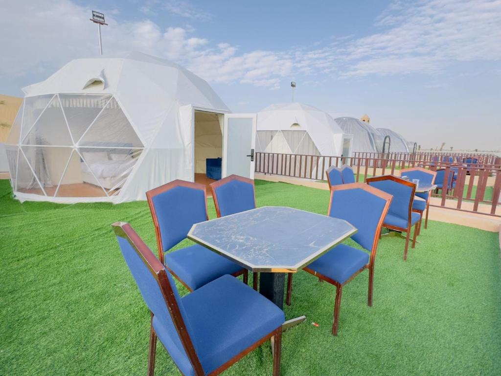 eine Gruppe von Stühlen, einem Tisch und einigen Zelten in der Unterkunft Desert Safari Dubai Over Night Stay in Hunaywah