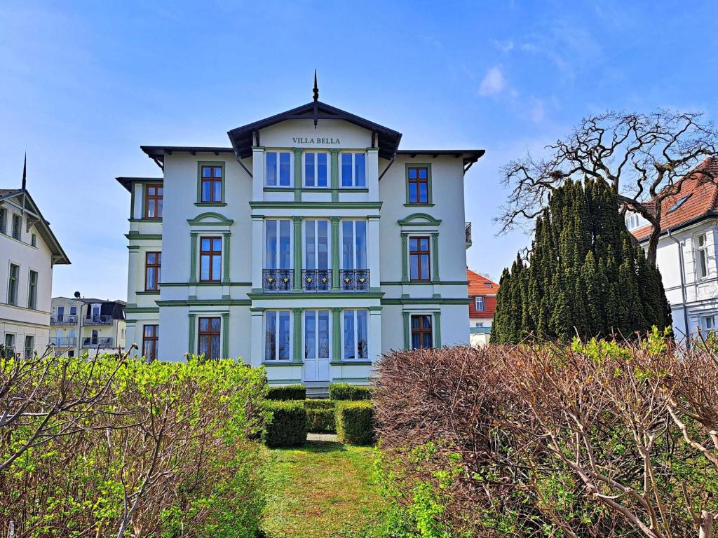ein großes weißes Haus mit blauen Fenstern in der Unterkunft Villa Bella - direkt an der Promenade in Ahlbeck
