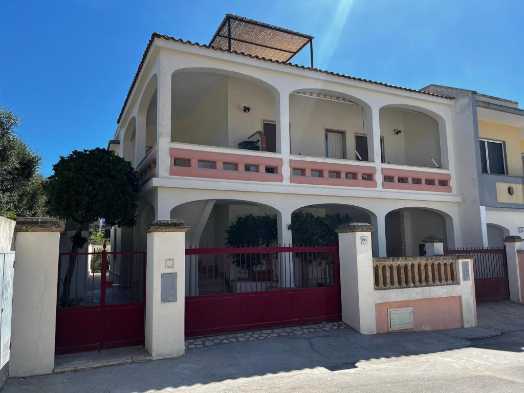 una gran casa blanca con una valla roja en Geko house, en Marina di Leuca