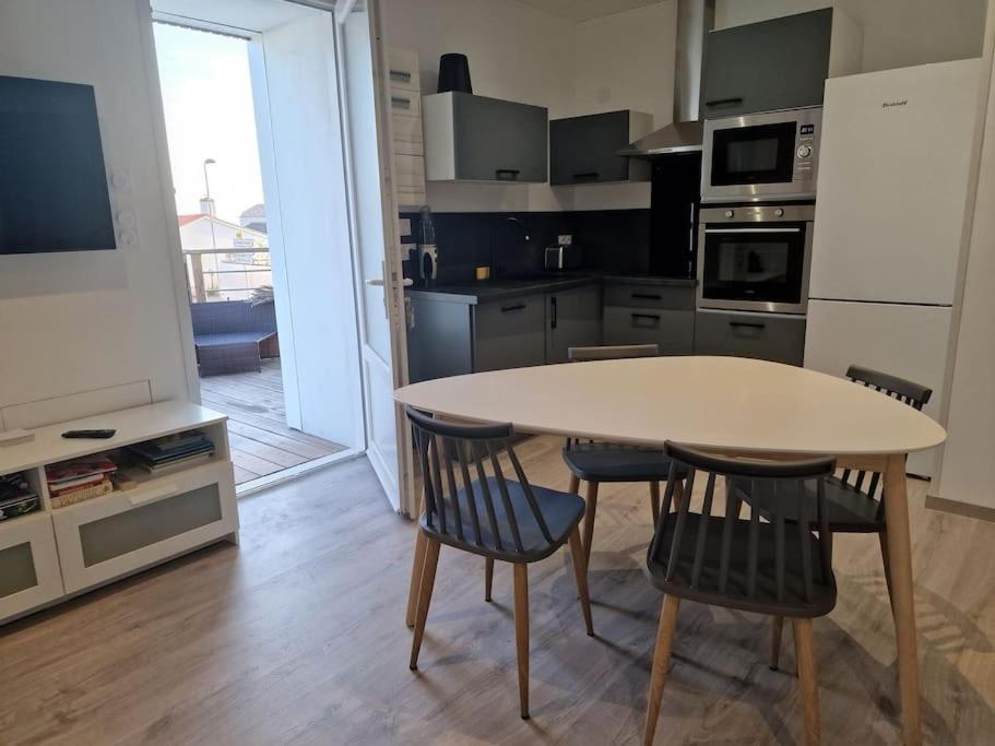 une cuisine avec une table et deux chaises ainsi qu'une télévision dans l'établissement Superbe appartement rénové à neuf centre bourg, à Brem-sur-Mer