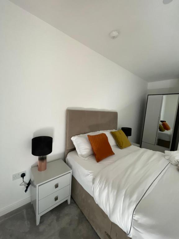 a bedroom with a bed and a night stand with a mirror at Upper executive apartment in Dagenham