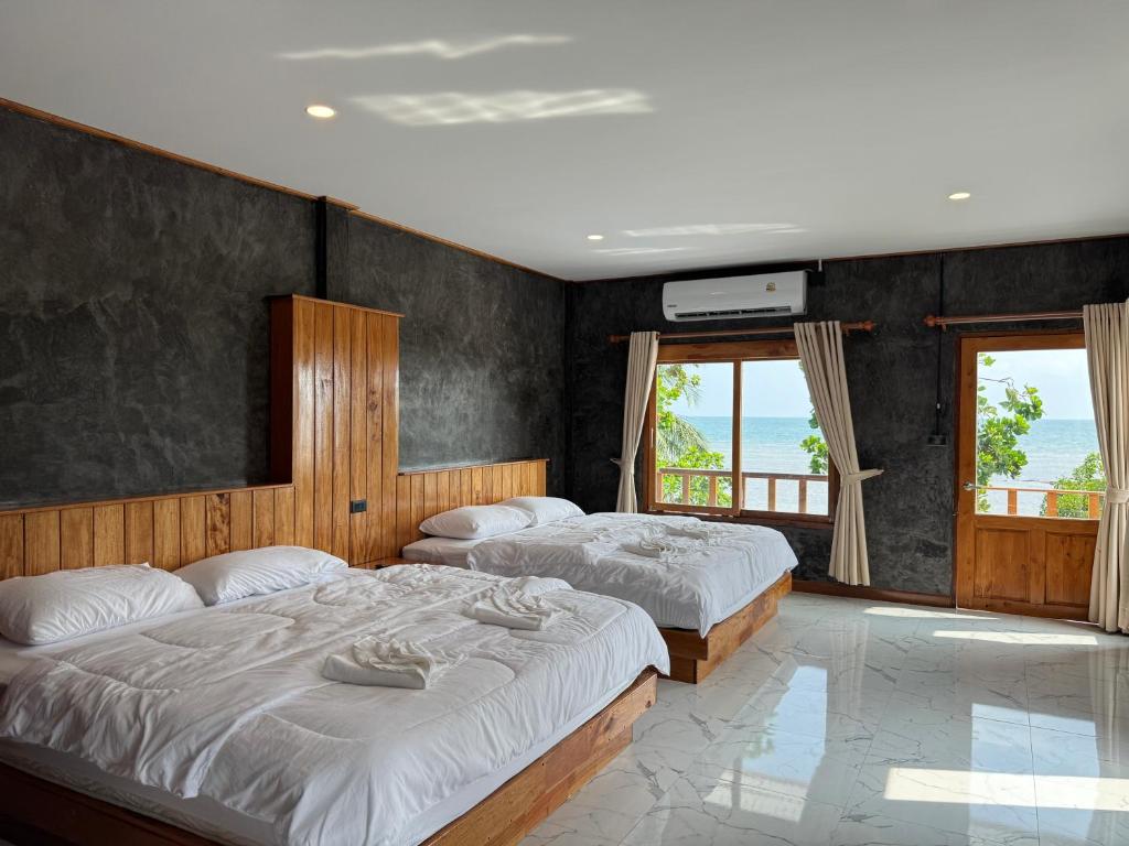 Libong Loft Home في ليبونغ: سريرين في غرفة بها نافذتين