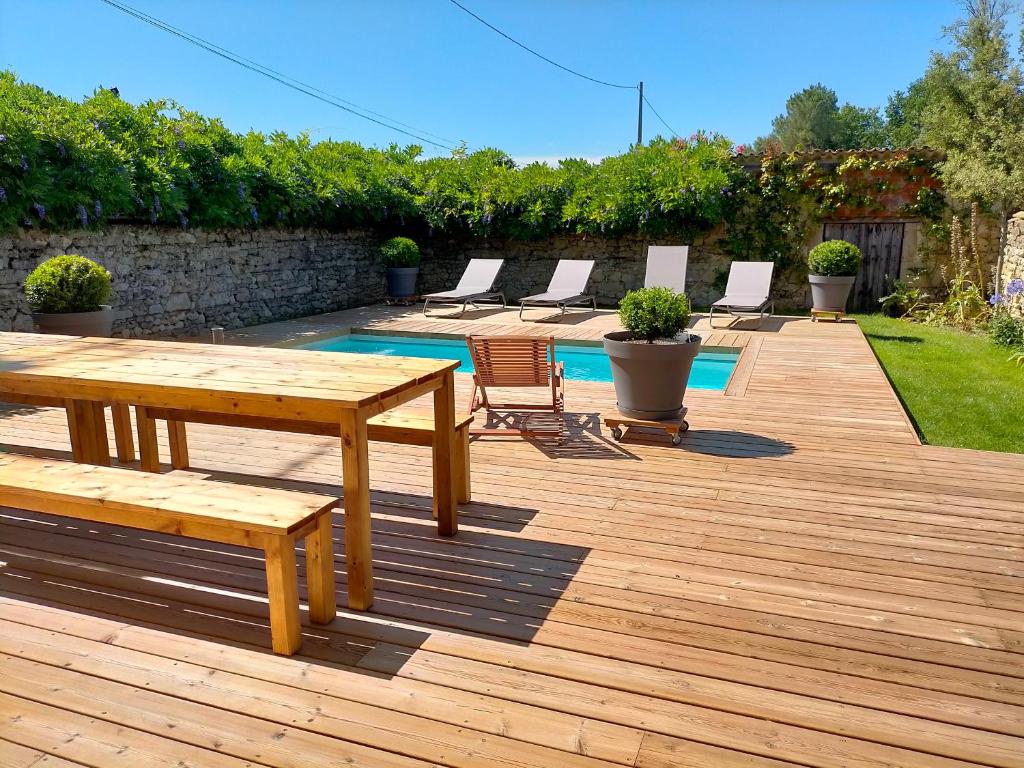 - une terrasse en bois avec une table et des chaises à côté de la piscine dans l'établissement Maison familiale de charme 11 personnes dans le Médoc, à Saint-Germain-dʼEsteuil
