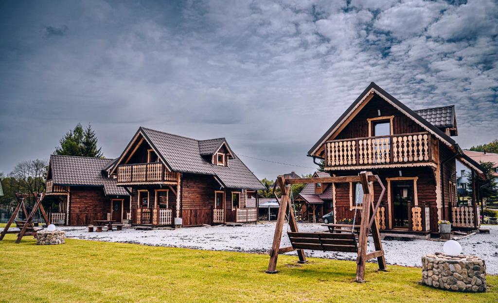 una casa de madera con un parque infantil delante de ella en Górskie Chatki Krysi i Piotrka Bursztynowy, en Stronie Śląskie