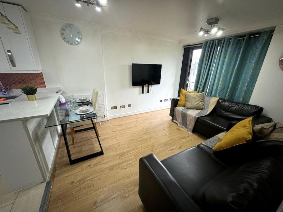 a living room with a couch and a table and a tv at Amazing Earls Court 2 bed Flat with Balcony in London