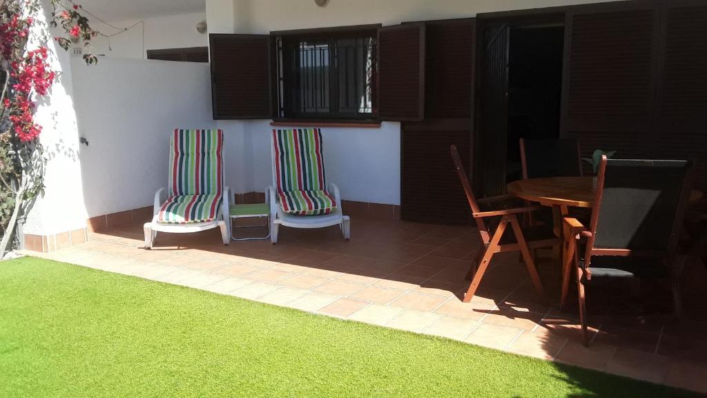 un soggiorno con tavolo, sedie e tappeto verde di Casa ARCO IRIS avec Jardin et Terrasse - piscine et jacuzzi partagés - by Cathy Ducoin a San Juan de los Terreros