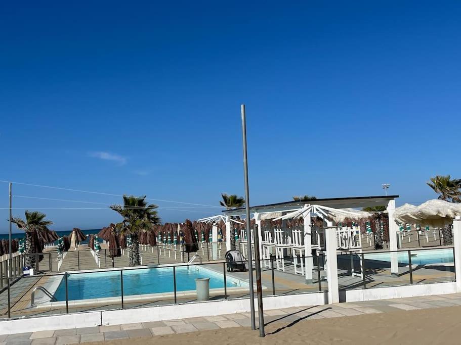 ein Pool mit Sonnenschirmen und das Meer im Hintergrund in der Unterkunft 4 SEASON SUITES 130mq AD UN PASSO DAL MARE con GYM PRIVATA in Pescara
