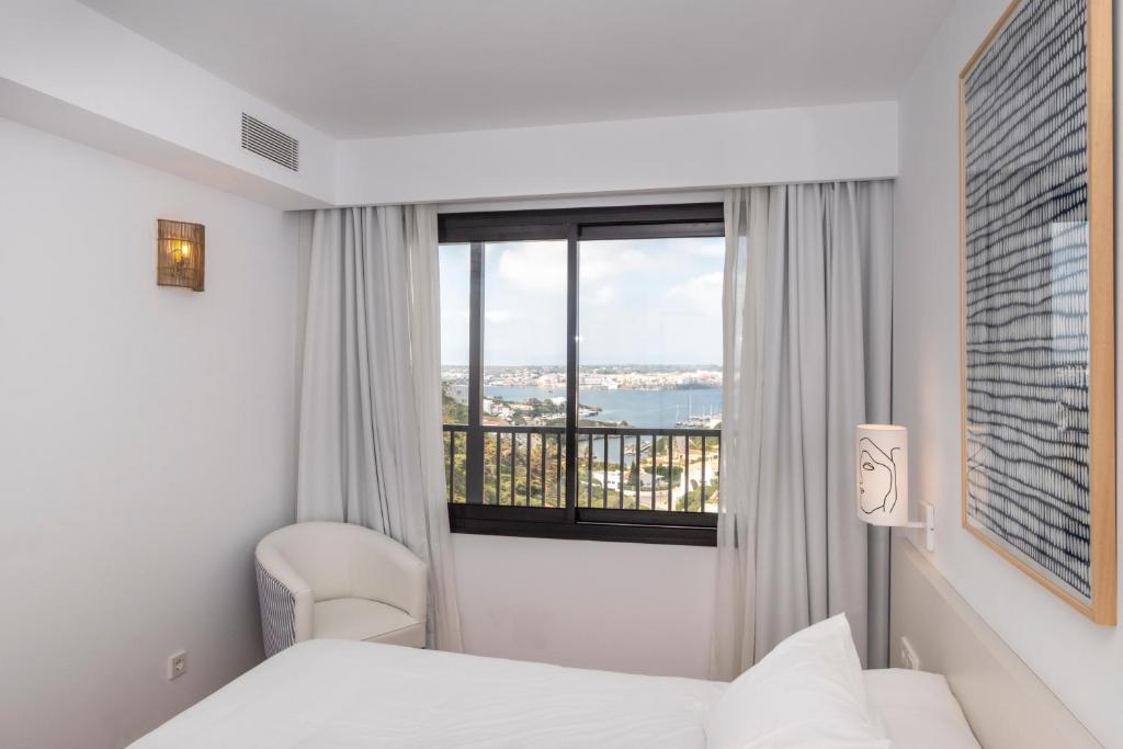 マオーにあるCalallonga Hotel Menorcaのベッド2台と窓が備わるホテルルームです。